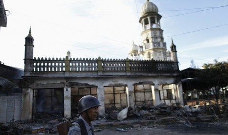 A police officer stands near a mosque which was burnt during a riot between Buddhist and Muslims in Lashio township May 29, 2013. 