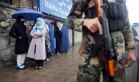 A policeman stands guard outside a polling station in Kabul as Afghans wanting to vote queue outside before it opened April 5, 2014.