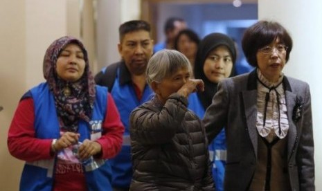 A relative (center) of a passenger aboard Malaysia Airlines MH370 reacts as she enters a meeting room with volunteers from Malaysia (in blue vests) at the Lido Hotel in Beijing March 27, 2014. 