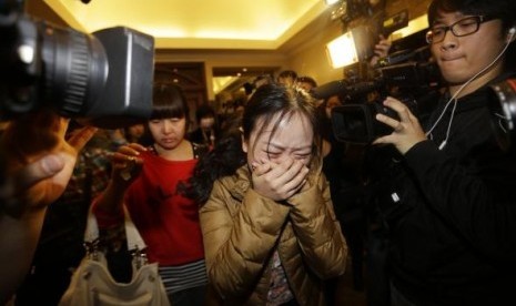 A relative (front) of a passenger of Malaysia Airlines flight MH370 cries as she walks past journalists at a hotel in Beijing March 9, 2014. 