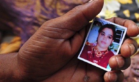 A relative holds a picture of a missing woman in front of the body of a garment worker who died in the collapse of the Rana Plaza building, in Savar, 30 km (19 miles) outside Dhaka April 25, 2013. 