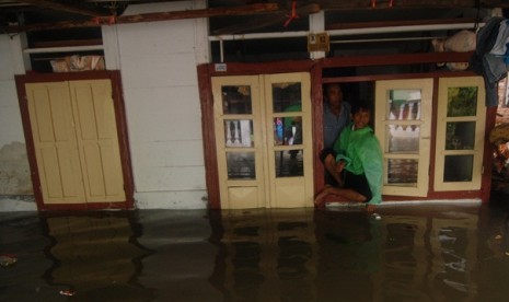 A residence keeps staying despite floods inundated their house in Manado, North Sulawesi, on Sunday.  