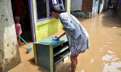 A resident use flood water to clean her furniture covered with mud from the previous flood in Kampung Melayu, East Jakarta. on Friday.  