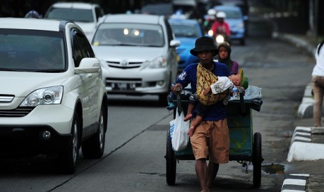 A scavenger pulls his cart while holds his child in Jakarta. Head of National Family Planning Coordinating Board (NFPCB) says that uncontrolled population growth may impact on many aspects of life, including problems in the economy and welfare. (illustrati