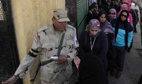 A soldier stands guard as women queue outside a polling center to vote in a referendum on Egypt's new constitution in Cairo January 14, 2014. 