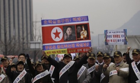 A South Korean protester holds a poster with photos of North Korean leader Kim Jong Un and late leader Kim Jong Il with writing reading 