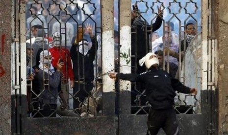 A student of Al Azhar University throws stones as another takes pictures during clashes with riot police and residents of the area at the Al-Azhar University campus in Cairo, on Friday.