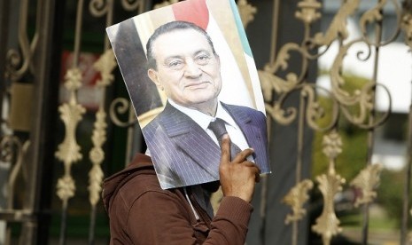 A supporter of Egypt's deposed president Husni Mubarak holds up his picture outside the Maadi Armed Forces hospital, where Mubarak is currently being held, in Cairo January 13, 2013.    