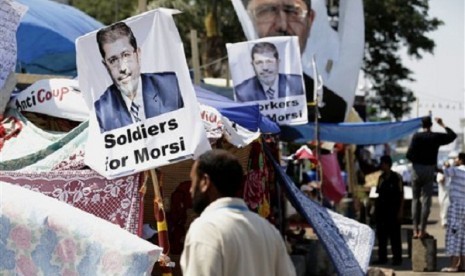 A supporter of Egypt's Islamist President Mohammed Mursi in front pictures of the president at Nasr City, Egypt, Thursday, July 25, 2013. 