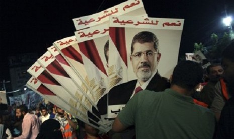 A supporter of Egypt's ousted President Mohammed Morsi holds his posters with Arabic writing which reads 