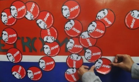 A supporter of Joko Widodo or Jokowi puts some stickers on a bus in Jakarta. (File photo)