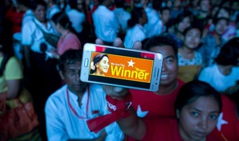 A supporter of Myanmar's National League for Democracy party displays her mobile phone with a picture of Suu Kyi as they gather to celebrate unofficial election results outside the NLD headquarters in Yangon, Myanmar, Monday, Nov. 9, 2015