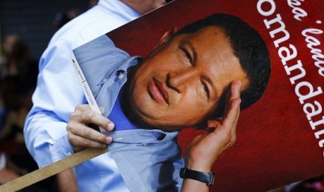 A supporter of Venezuelan President Hugo Chavez holds a picture of him as he takes part in a gathering at Plaza Bolivar in Caracas on Monday.