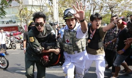 A suspected gunman (center bottom) is carried to an ambulance when he was caught and beaten by anti-government protesters after allegedly firing a pistol at protesters during a rally outside the Army Club Tuesday, Jan. 28, 2014 in Bangkok, Thailand. 