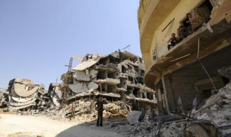 A Syrian army soldier loyal to Syria's President Bashar al-Assad chats with fellows sitting on a balcony of a damaged building in Mleiha, on August 15, 2014.