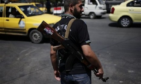 A Syrian military soldier holds his AK-47 with a sticker of Syrian President Bashar Assad and Arabic that reads, 