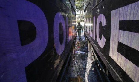 A Thai security personnel inspects destroyed police trucks at the Thai-Japan youth stadium, the site of fierce clashes between anti-government protester and riot police, in central Bangkok December 27, 2013.