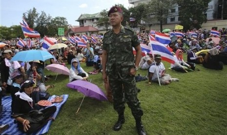 A Thai soldier stands as anti-government protesters sit at the Royal Thai Army compound in Bangkok, Thailand, Friday, Nov. 29, 2013. 