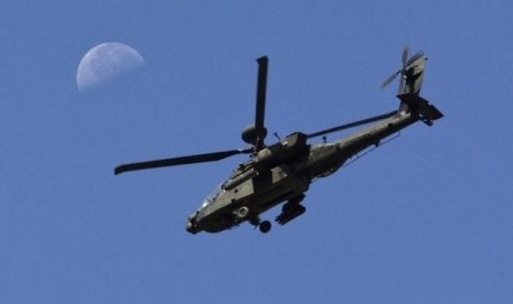 A U.S. Army Apache flies past the moon in the Zharay district of Kandahar province, southern Afghanistan June 11, 2012.