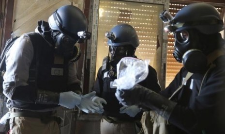 A UN chemical weapons expert, wearing a gas mask, holds a plastic bag containing samples from one of the sites of an alleged chemical weapons attack in the Ain Tarma neighbourhood of Damascus August 29, 2013.