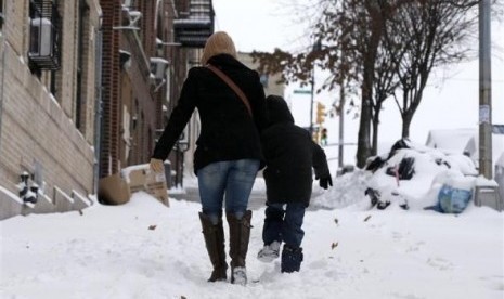 A woman and her son make their way up a snow covered sidewalk in the South Bronx section of New York City, January 3, 2014.