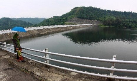 A woman and her son pass at the bank of a a reservoir (illustration)