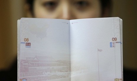  A woman holds a Chinese passport, displaying a Chinese map which includes an area in the South China Sea inside a line of dashes representing maritime territory claimed by China (left, top) and a picture of Beijing's Tiananmen Square (bottom), at an office in Wuhan airport, Hubei province, November 23, 2012. 