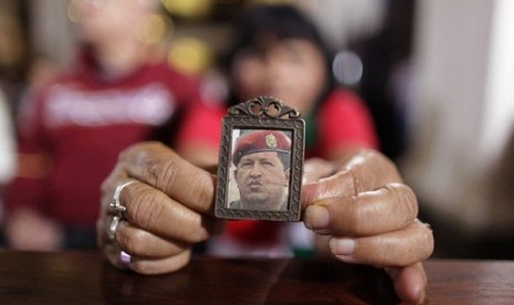 A woman holds an image of Venezuela's President Hugo Chavez as people gather to pray for him at a church in Caracas, Venezuela, Monday, Dec. 31, 2012.   