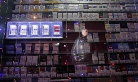 A woman is reflected in a window displaying packs of cigarettes on a street in Russia's Siberian city of Krasnoyarsk January 24, 2013.