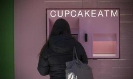 A woman makes a purchase from the Cupcake ''ATM'' at Sprinkles Cupcake Bakery in New York City's Upper East Side in Manhattan, March 26, 2014.