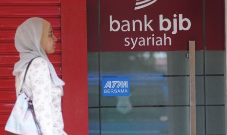 A woman passes Bank Syariah BJB's automatic teller machine (ATM). 