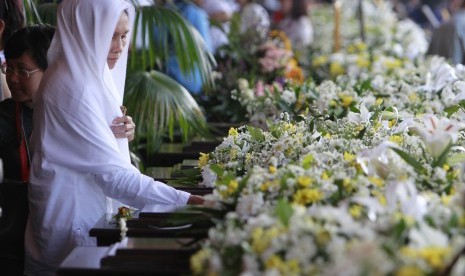 A woman places a hand on the coffin of one of the victims of a Russian Sukhoi Superjet 100 plane that crashed on Salak Mountain, during a ceremony at Halim Perdanakusuma airport in Jakarta on Wednesday. The remains of all 45 victims of the crash were officially handed over to their families.