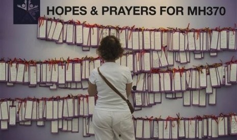 A woman read message cards tied up for passengers aboard a missing Malaysia Airlines plane, at a shopping mall in Kuala Lumpur, Malaysia, Monday, March 24, 2014. A