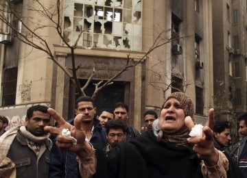 A woman shouts about the political situation in the country, in front of a damaged government building near the Interior Ministry in Cairo, Egypt, on Wednesday. 