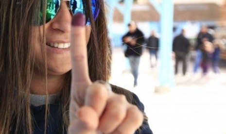 A woman shows her ink-stained finger after casting her vote at a polling station in Tunis December 21, 2014.