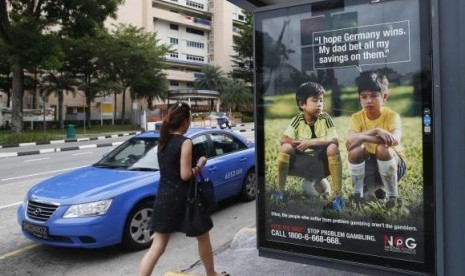 A woman walks past a World Cup anti-gambling advertisement at a taxi stand in Singapore July 9, 2014.