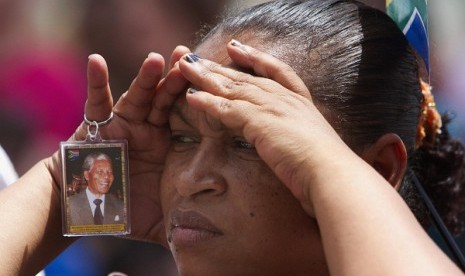 A woman watches the funeral service for former South African President Nelson Mandela on a large screen television on Cape Town's Grand Parade, December 15, 2013. Mandela was buried at his home in Qunu in the Eastern Cape province. 