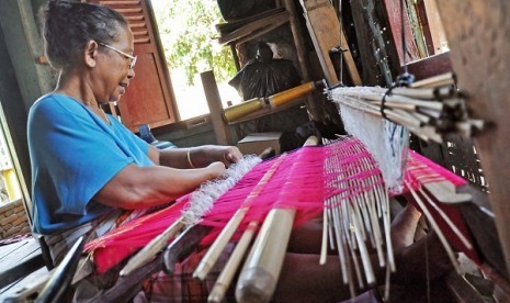 A woman weaves a piece of traditional woven fabric of West Nusa Tenggara. (illustration)      