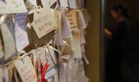 A woman writes another message of hope and support for the passengers of the missing Malaysia Airlines MH370 at a mall outside Kuala Lumpur March 22, 2014. 