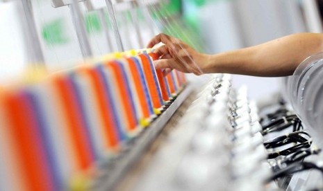 A worker checks the threads in embroidery machine at an exhibition in Jakarta.  