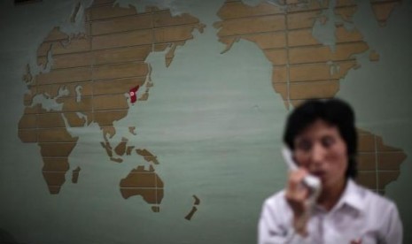 A world map, with the Korea peninsula marked in red, is seen as a hotel receptionist talks on the phone in Rason city, northeast of Pyongyang, August 29, 2011.