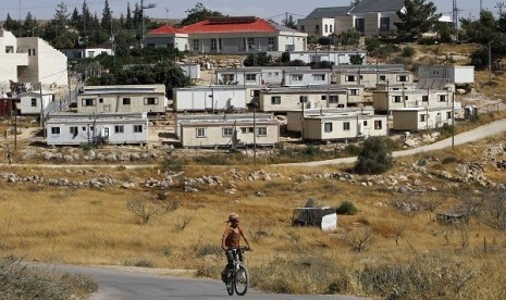 A young Jewish settler rides a bicycle in front of the West Bank settlement of Susiya June 24, 2012. Susiya the settlement enjoys well-watered lawns, humming electricity, and the protection of a mighty state. One rocky hill away, Susiya the Palestinian vil