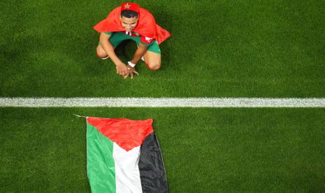  Abdelhamid Sabiri dari Maroko merayakan, duduk di dekat bendera Palestina, setelah pertandingan sepak bola babak 16 besar Piala Dunia antara Maroko dan Spanyol, di Stadion Education City di Al Rayyan, Qatar, Selasa, 6 Desember 2022.