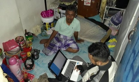 Abdori hendak beristirahat di kamar sewaan di daerah Kebon Kosong, Kemayoran, Jakarta Pusat, setelah seharian bekerja sebagai supir bajaj BBG. Anaknya, Aris Munandar, sedang sibuk dengan laptopnya. 