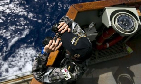 Able Seaman Boatswains Mate Marc Chandler looks through a pair of binoculars aboard the Australian Navy ship HMAS Success. as it continues to search for missing Malaysian Airlines flight MH370.