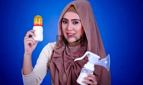 Ibu memegang botol air susu ibu (ASI) dan alat pemerah ASI. Promosi susu formula menghambat kampanye pemberian ASI.