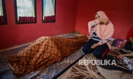 Adik dari korban minuman keras (miras) oplosan menangis di rumah duka setelah dibawa dari Rumah Sakit Umum Daerah Cicalengka (RSUD), Kabupaten Bandung, Jawa Barat, Jumat (13/4).