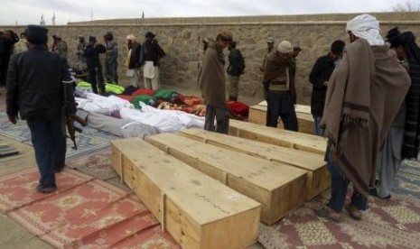 Afghan men gather around the bodies of victims of Sunday's suicide attack at a volleyball match in Yahya Khail district, Paktika province, November 24, 2014.