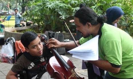 Ages Dwi Harso, pendiri komunitas Taman Suropati Chambers mengajarkan seorang anak bermain Cello