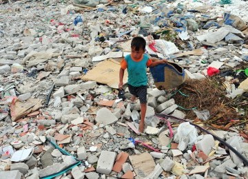 Ahmad (6), mencari sampah plastik diantara tumpukan sampah dan limbah bekas pembangunan proyek di kawasan Muara Angke, Jakarta Utara, Selasa (31/1). (Republika/Edwin Dwi Putranto)